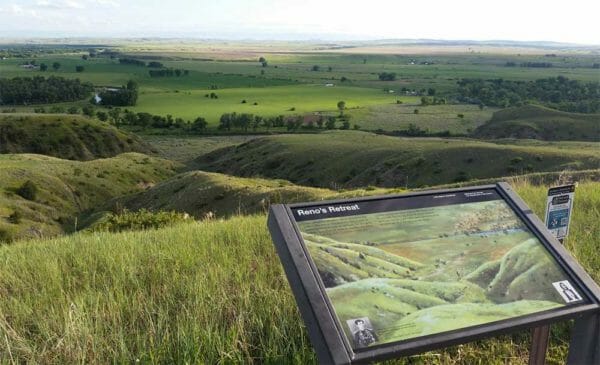 A plaque labeled “Reno’s Retreat” marks a spot at the Little Bighorn National Battlefield. In the background is a field of rolling green hills. Battlefield Road is a nearly five-mile, self-guided vehicle tour that takes visitors to the spot where the first shots were fired at the Battle of Little Bighorn, June 25, 1876. It’s where most of the U.S. 7th Cavalry Regiment was surrounded by the combined forces of several Northern Plains American Indian tribes. About 7,000 Lakota, Sioux, Cheyenne and Arapahos were camped in the Little Bighorn River Valley, near what is now Garryowen, Mont., when the cavalry led by Lt. Col. George Custer attacked them.